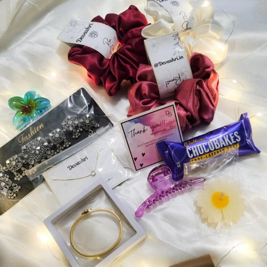 Collection of beauty products including hair ties, a necklace, a bracelet, and a chocolate bar on with decorative lights. A gifting Hamper for lovers, wife or Gf , girlfriends, sister.