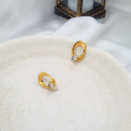 Gold earrings with a pearl center on a white surface